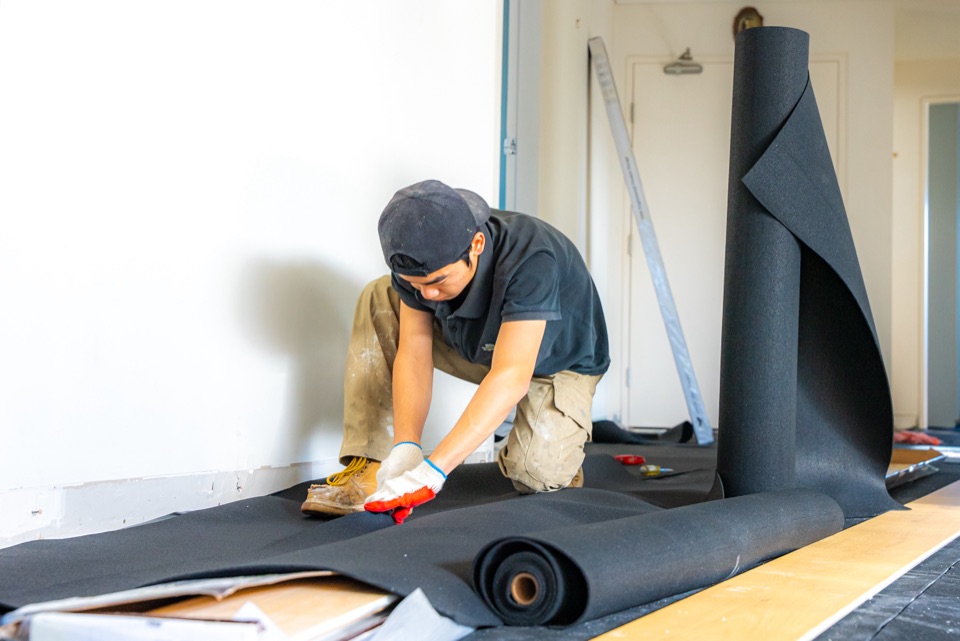 Rolling out acoustic underlay along the hallway