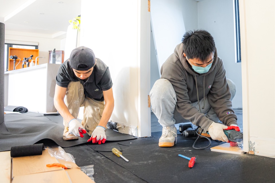 Two installers fitting underlay at the doorway