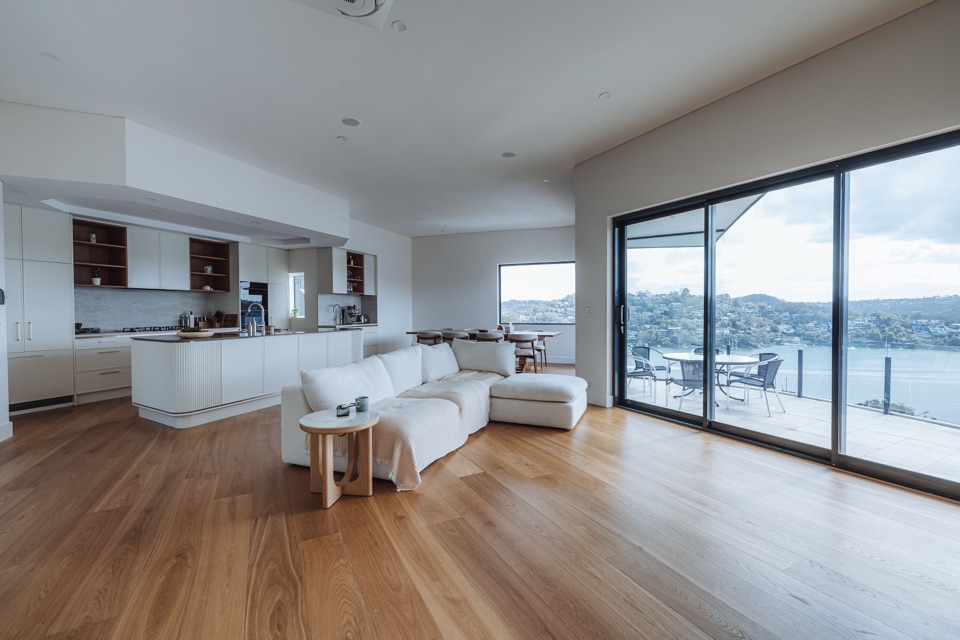 Open-plan living and kitchen in European oak, with the harbour through the sliders