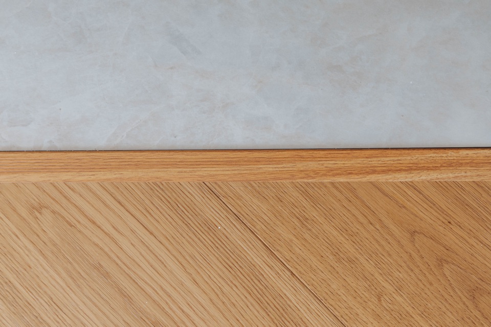 A mitred oak border where the floor meets the stone