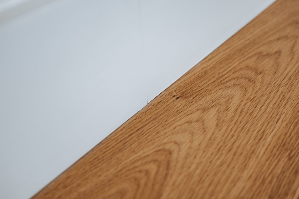The board edge along the wall, closer